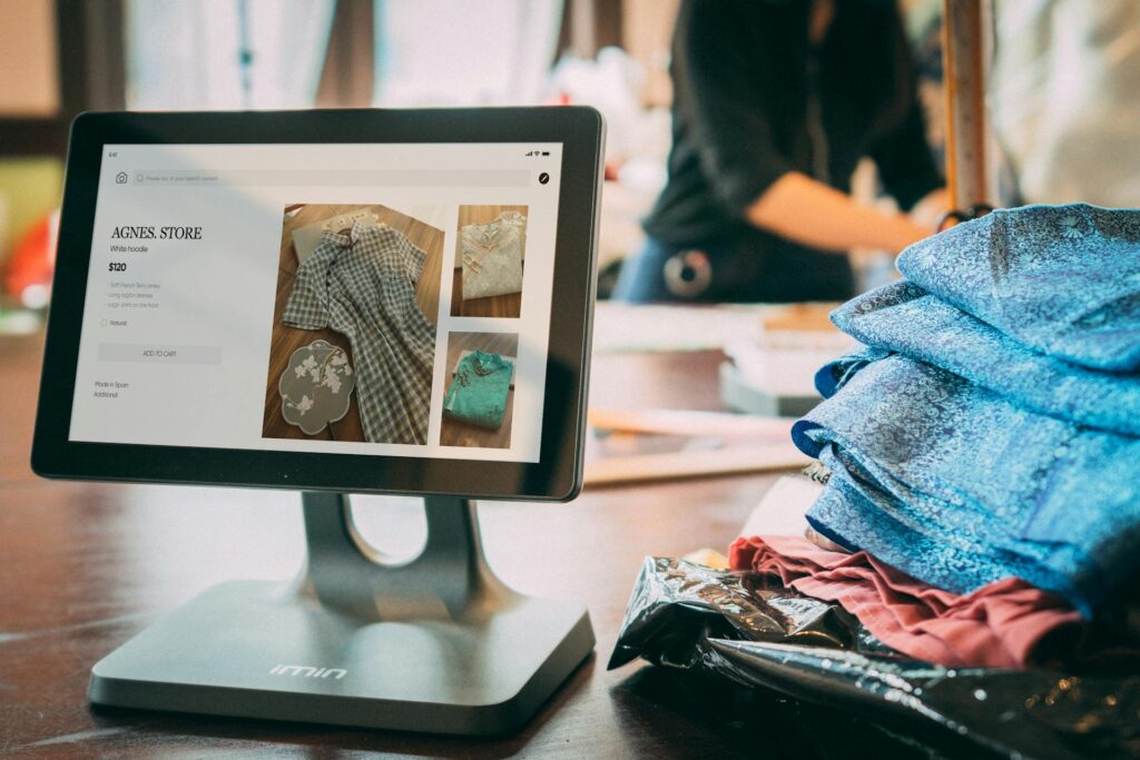 A digital point-of-sale system in a small fashion boutique with clothes displayed on a tablet - ai shopper marketing technolo