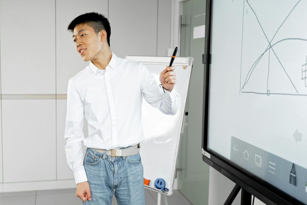 Ogilvy’s “Human Premium”: Why Authenticity Outperforms Pure AI Automation Asian man presenting with smart board in a modern office setting - ogilvy human premium